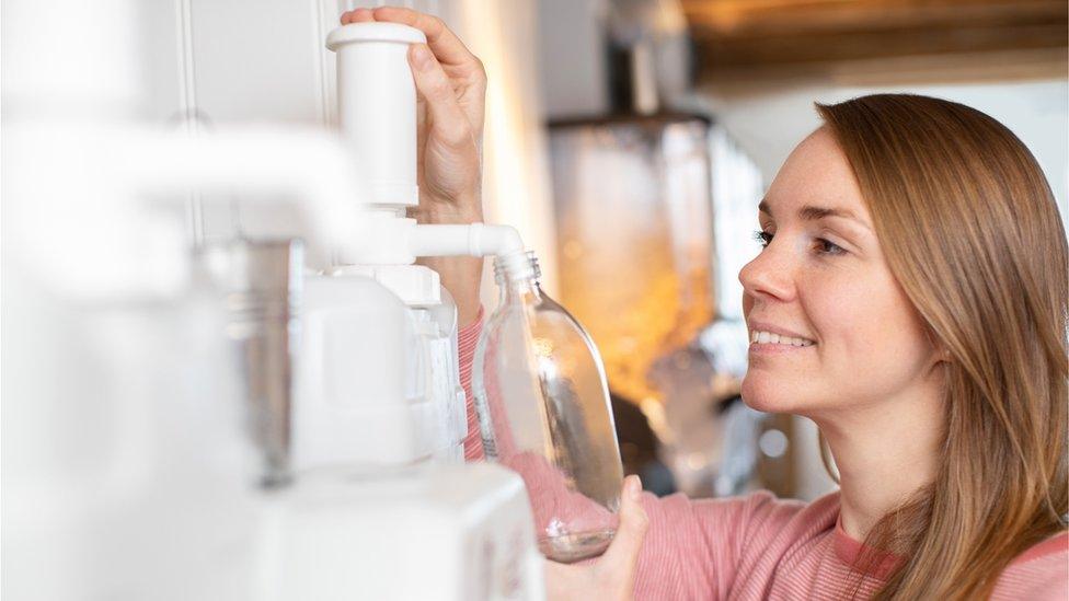 A woman filling container with cleaning product in Plastic Free Grocery Store