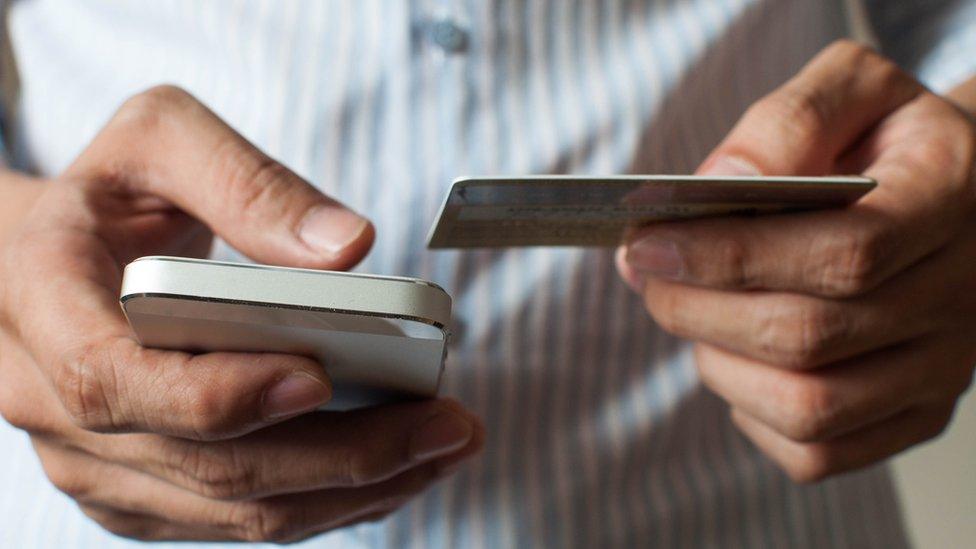 Person holding phone and bank card