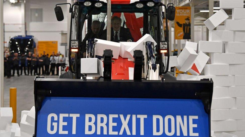 Boris Johnson drives a Union flag-themed JCB, with the words "Get Brexit Done" inside the digger bucket