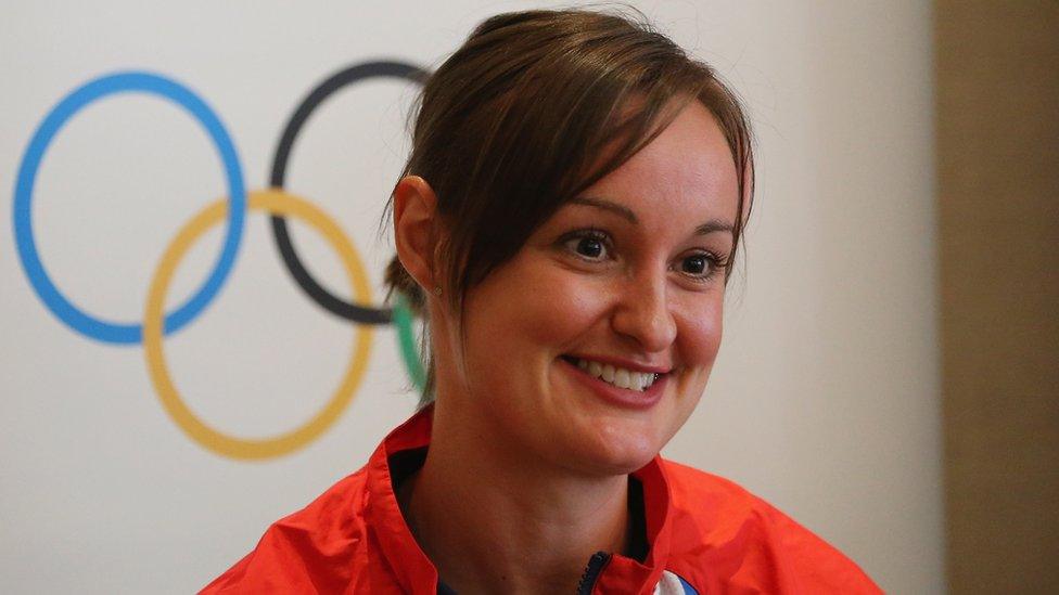 Susan Egelstaff smiling with the Olympic rings symbol in the background