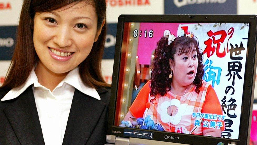 woman holding 2004 Toshiba laptop