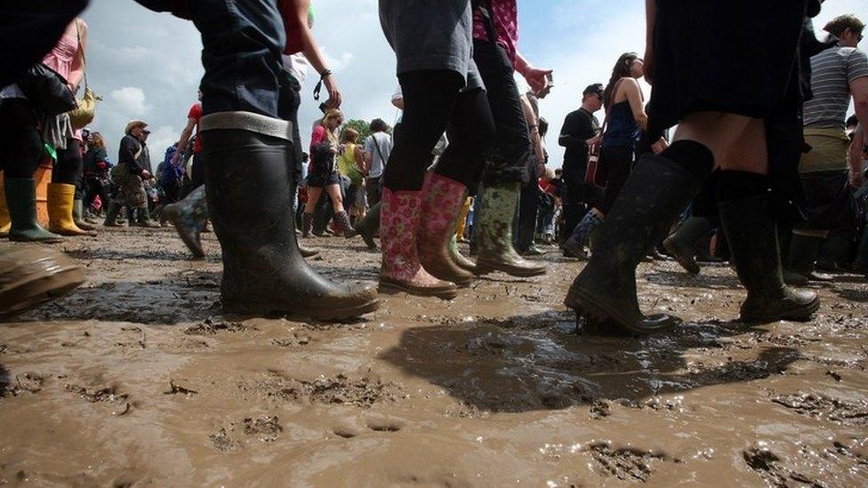 Glastonbury Festival goers walking through muddy areas