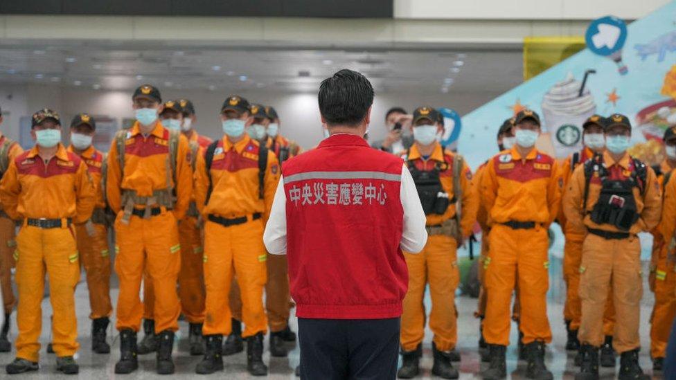 A Taiwanese official stands in front of a group of rescuers