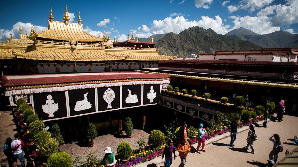 Chinese tourists on the roof of the Jokhang Temple in Lhasa, with mountains seen in the background