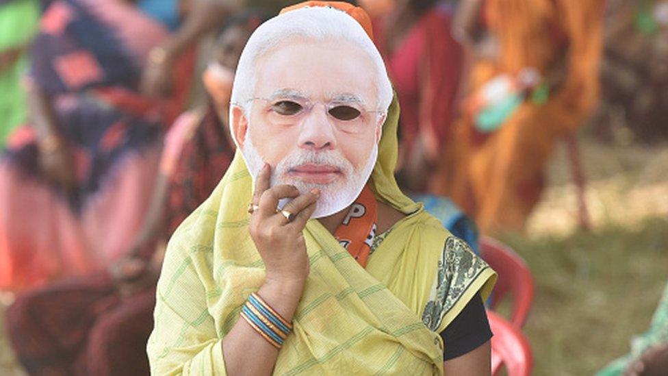 A woman holds up a mask of PM Narendra Modi's face during his rally for Bihar assembly election on October 23, 2020 in Sasaram, India