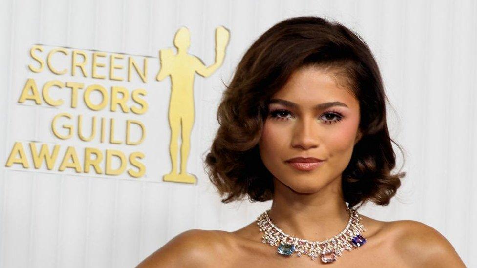 Zendaya with medium-length brown hair wearing a necklace at an award ceremony