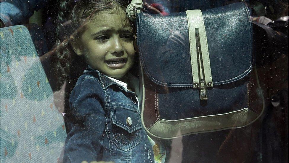 A girl cries as she waits on a bus which will transport her family to the tube station, after their arrival from the north-eastern Greek island of Lesbos to the Athens port of Piraeus on 8 September 2015