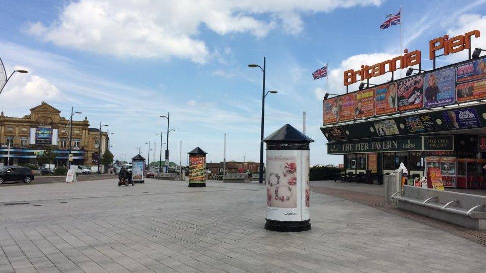 Seaside pier and paved area with litter bins