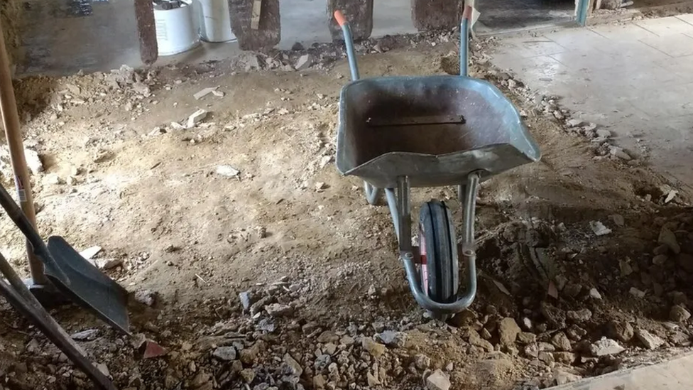 Wheelbarrow and dug up floor