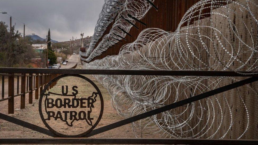 A metal fence marked with the US Border Patrol sign prevents people to get close to the barbed/concertina wire covering the US/Mexico border fence, in Nogales, Arizona, on February 9, 2019