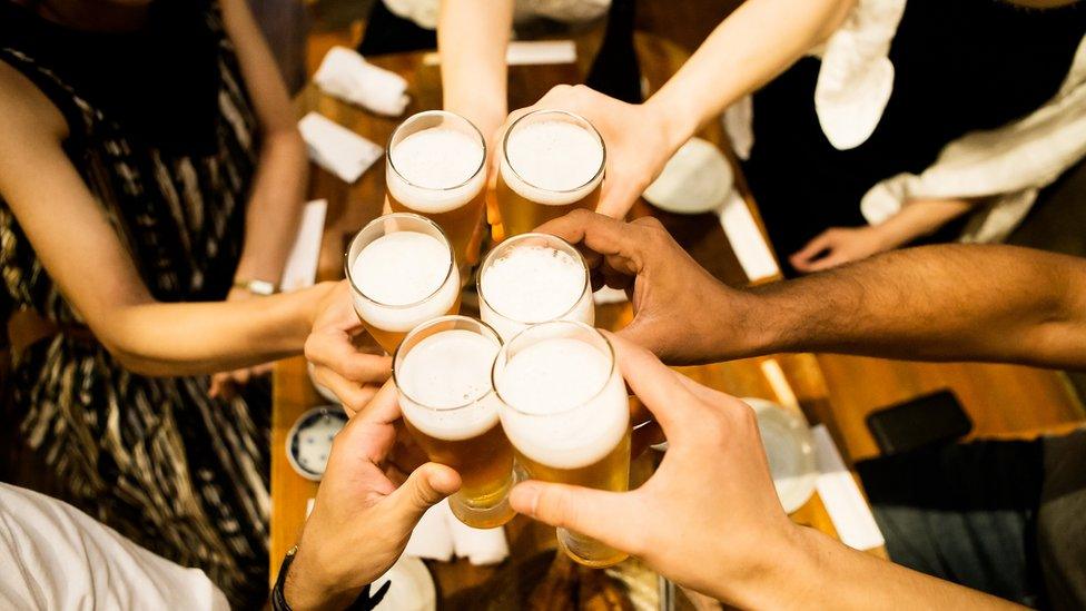 people clinking pint glasses in pub