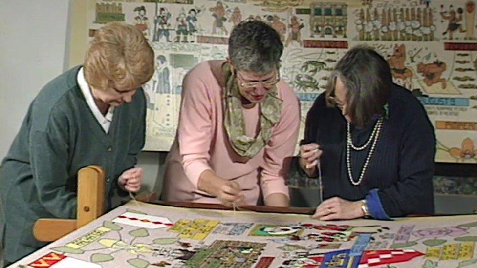 Volunteers stitch the New World Tapestry