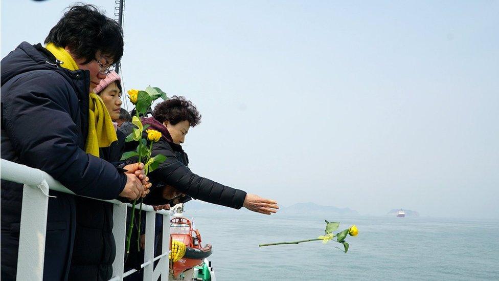 A family member of victims drops a yellow flower into the sea during a memorial ceremony at sea off Jindo, South Korea, in this handout picture provided by the Ministry of Oceans and Fisheries and released by Yonhap on March 28, 2017.