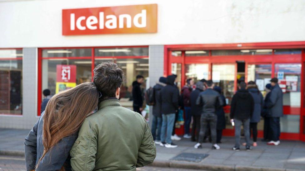 Shoppers look at a queue outside Iceland