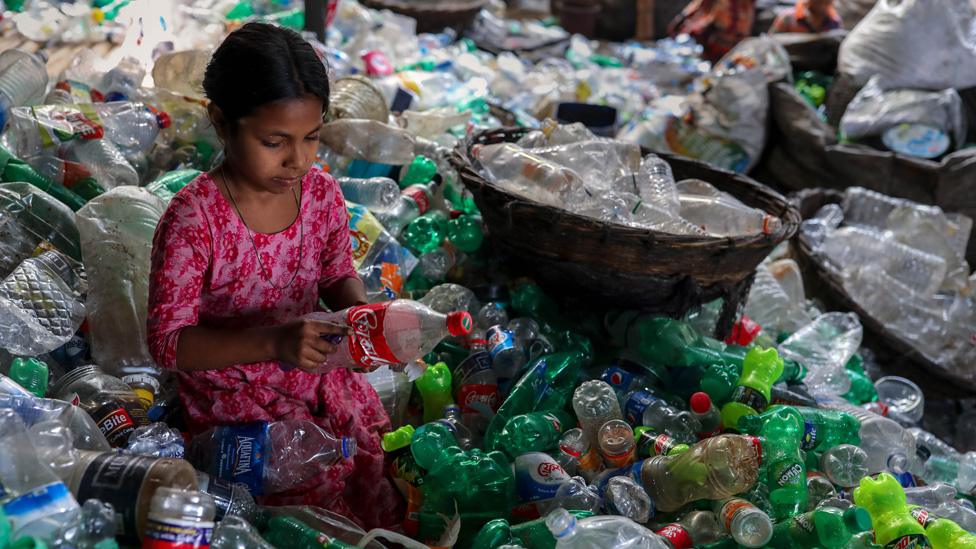 A girl sorts through plastic recycling in Bangladesh