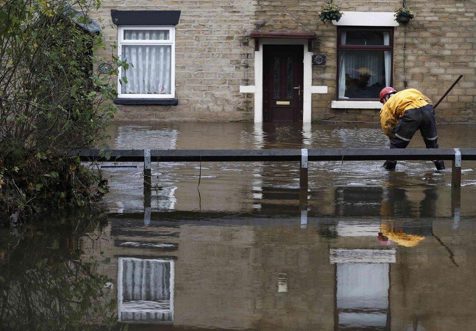 An emergency services worker stands in flood water in Stalybridge