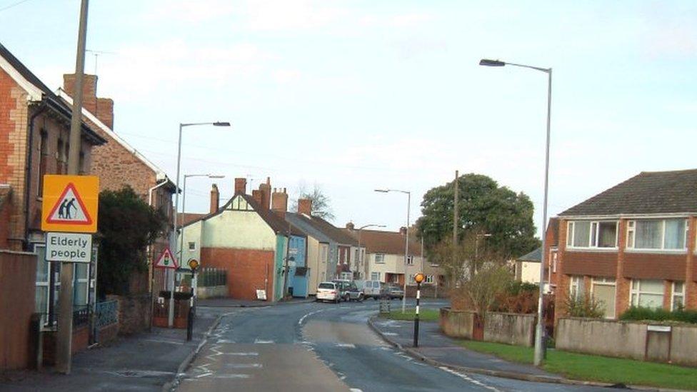 A road through houses and with a street sign saying 'elderly people'