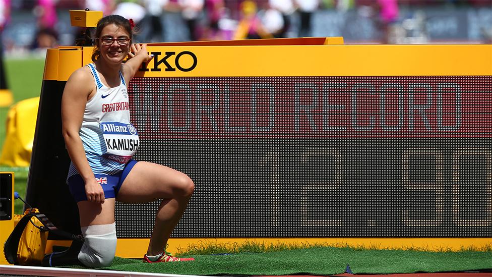 Sophie Kamlish, kneeling near a world record board with a trainer and running blade