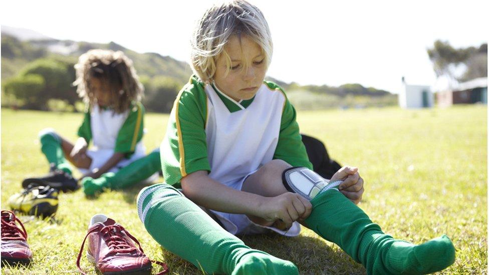 Child putting on shin pads