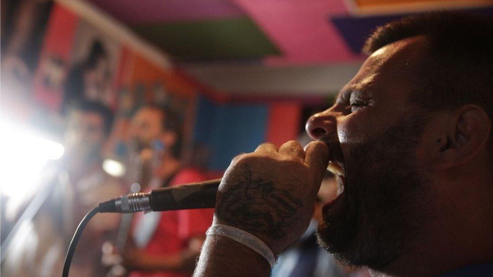 Adrian Baraldo sings into a microphone in the music studio at Punta de Rieles