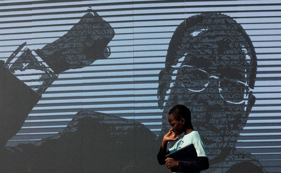 A young boy walks past a digital image of late former Zimbabwean president Robert Mugabe as his body lies in state at Murombedzi Growth Point, about 107 km northwest of Harare, Zimbabwe, on September 16, 2019