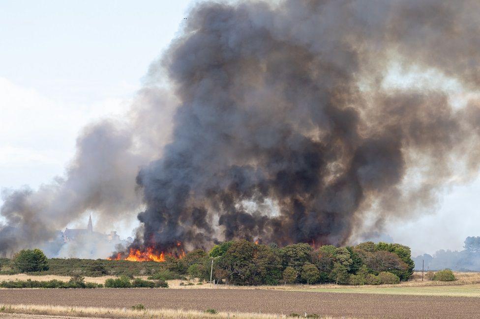 Smoke billowing into the sky in a rural landscape