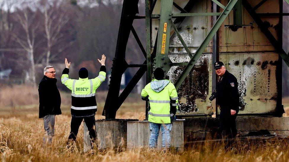 Workers inspect the damaged pylon