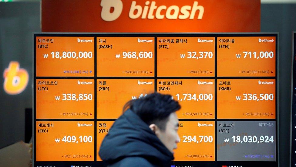 A man walks past an electric board showing exchange rates of various crypto-currencies including Bitcoin (top L) at a crypto-currencies exchange in Seoul, South Korea on 13 December 2017