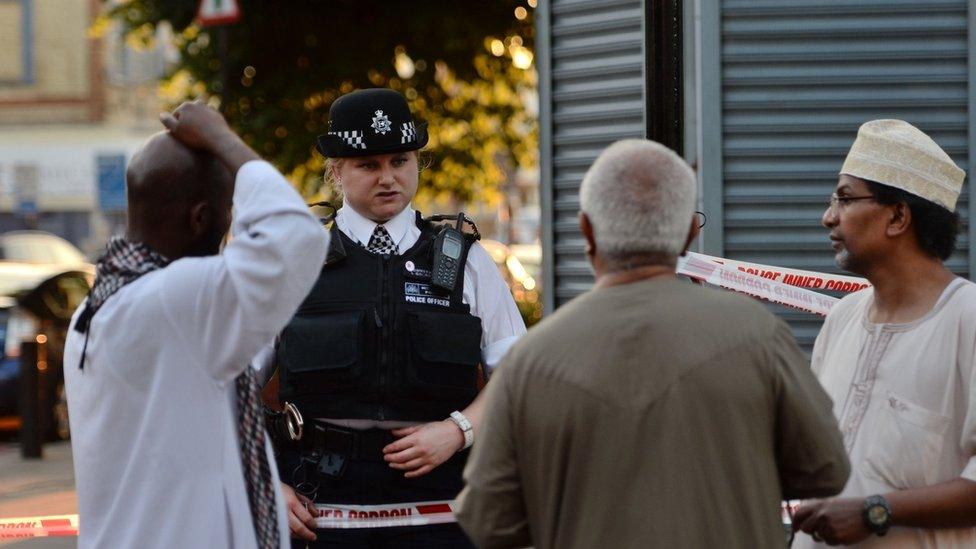 A police officer talks to local people at Finsbury Park in north London, where one man has died, eight people taken to hospital