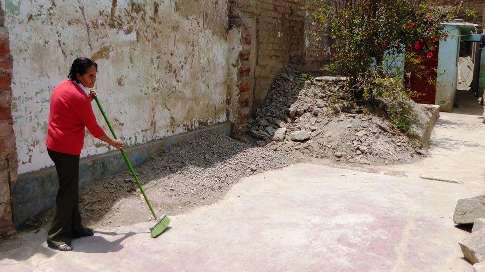 Natividad de la Cruz sweeps the dust in what used to be her house in Moyopampa