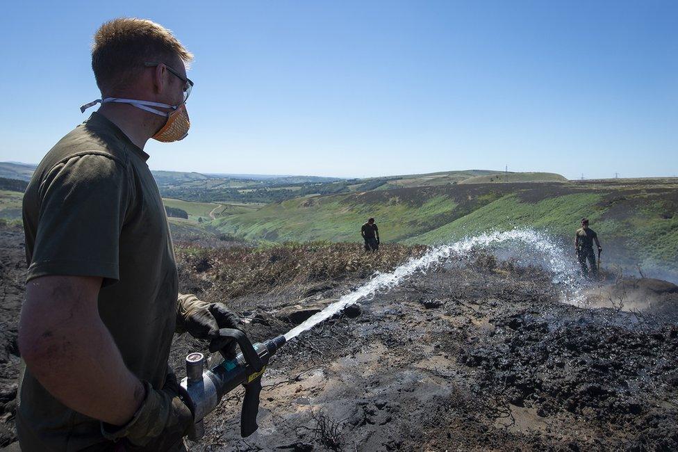 Person spraying a hose on burning moorland