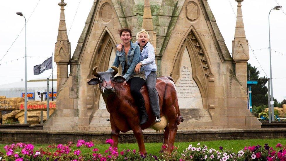 People on a plastic cow in Skegness