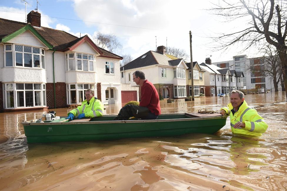 A resident is rescued from a home in a boat by the emergency services amid flooding in Hereford.