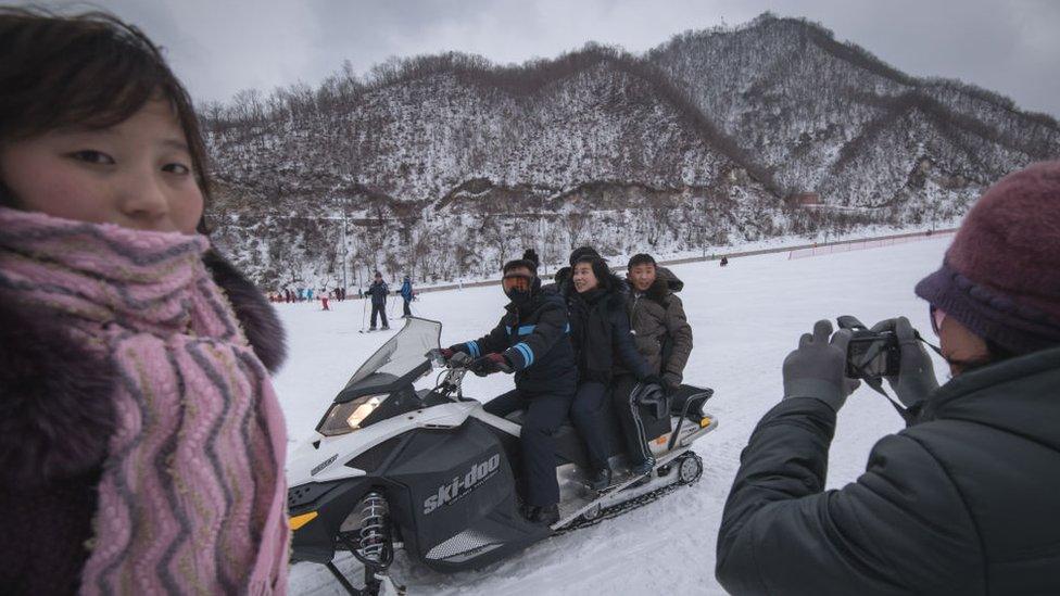 This photo taken on February 19, 2017 shows North Korean visitors posing on a snowmobile at the Masikryong ski resort,