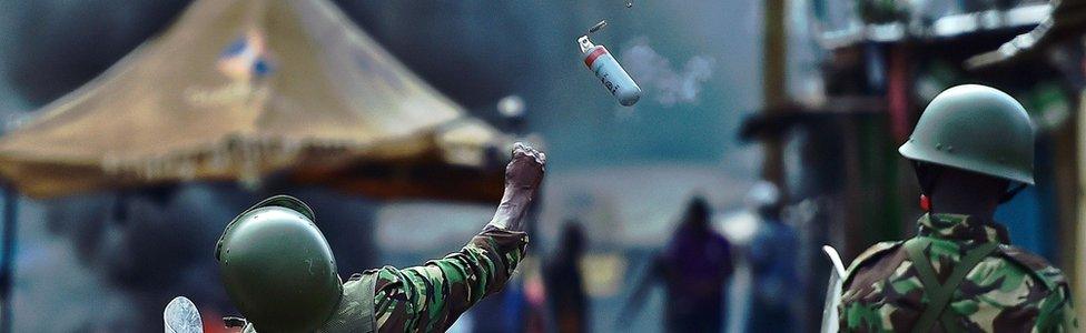 A riot policeman in Kenya throws a tear gas canister