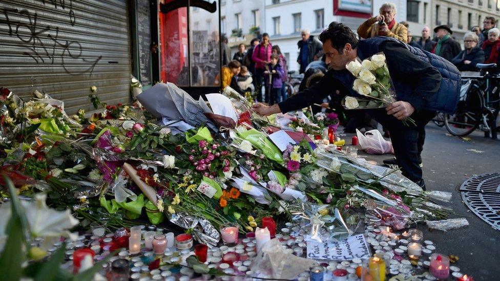 A man places a flower the scene of the attack at the La Belle Equipe restaurant