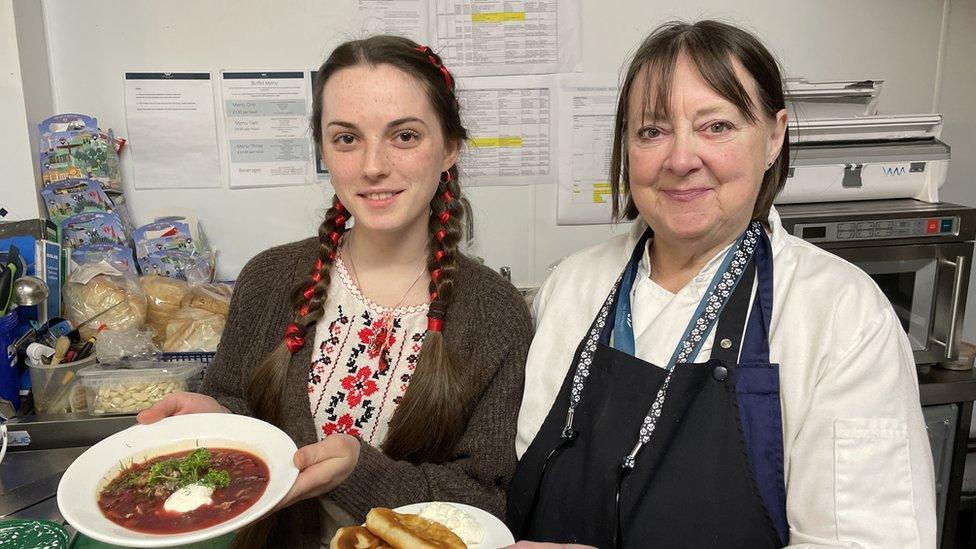 Hanna Hyrka and Jayne Wynne holding up dishes of traditional Ukrainian food