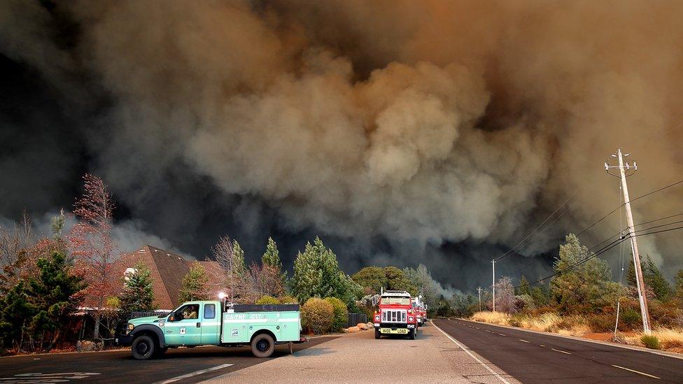 A plume of smoke rises above the Camp Fire as it moves through the area