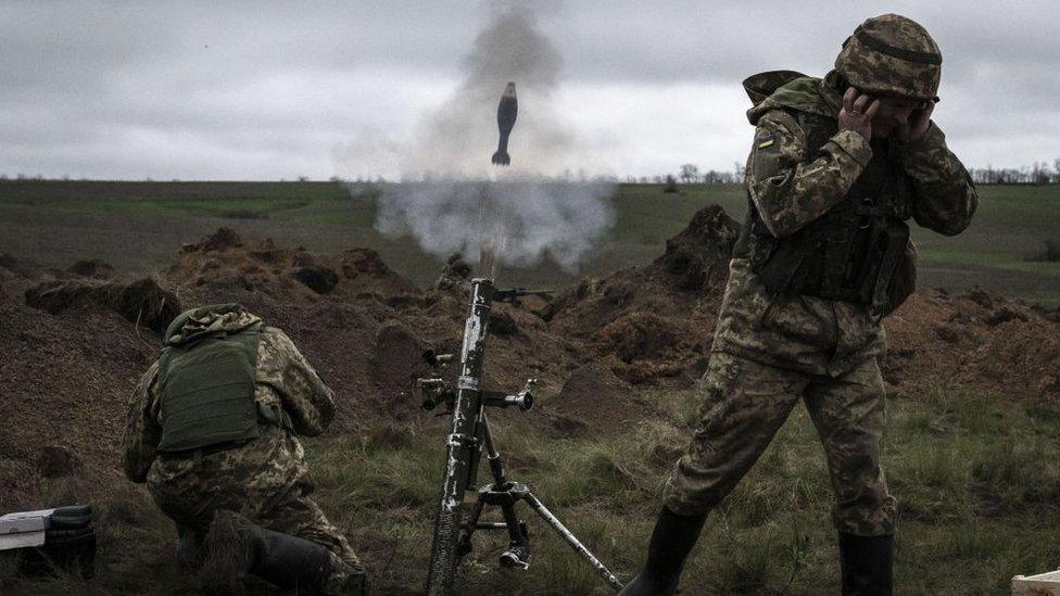 Ukrainian soldiers fire a mortar