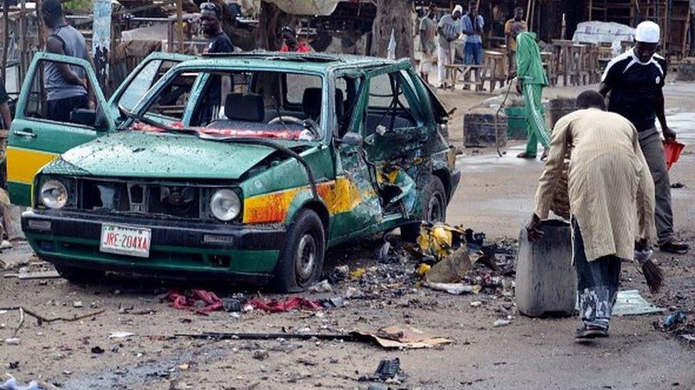 A man scouts for valuables beside a taxi damaged following an Improvised Explosive Devices (IED) at Gomboru market in Maiduguri, Borno State in northeastern Nigeria on July 31, 2015 detonated by a female suicide bomber who arrived on a taxi tricycle killings at least eight people and several other