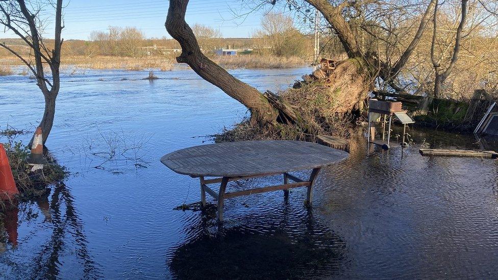 The flooding in Britford from someone's flooded garden, showing everything covered in water and merging with the river