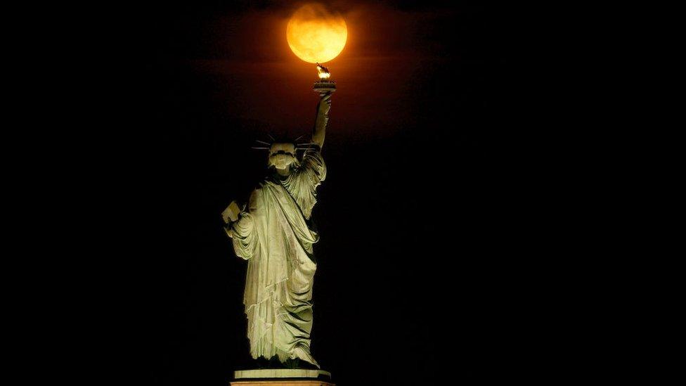 Buck Moon rising behind the Statue of Liberty in the US city of New York