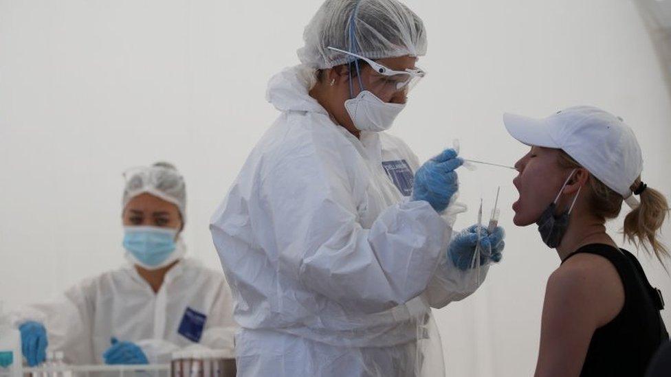 A health worker takes a swab from a woman at a mobile testing station in Almaty, Kazakhstan. Photo: June 2020