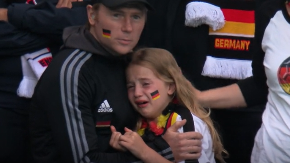 A young Germany fan crying while being hugged