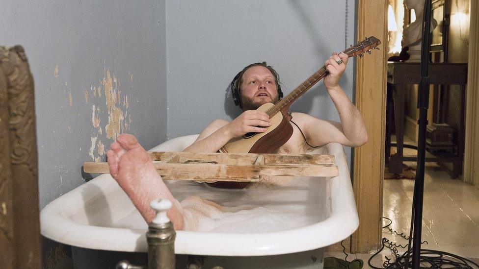 Photo of Ragnar Kjartansson playing guitar in the bath