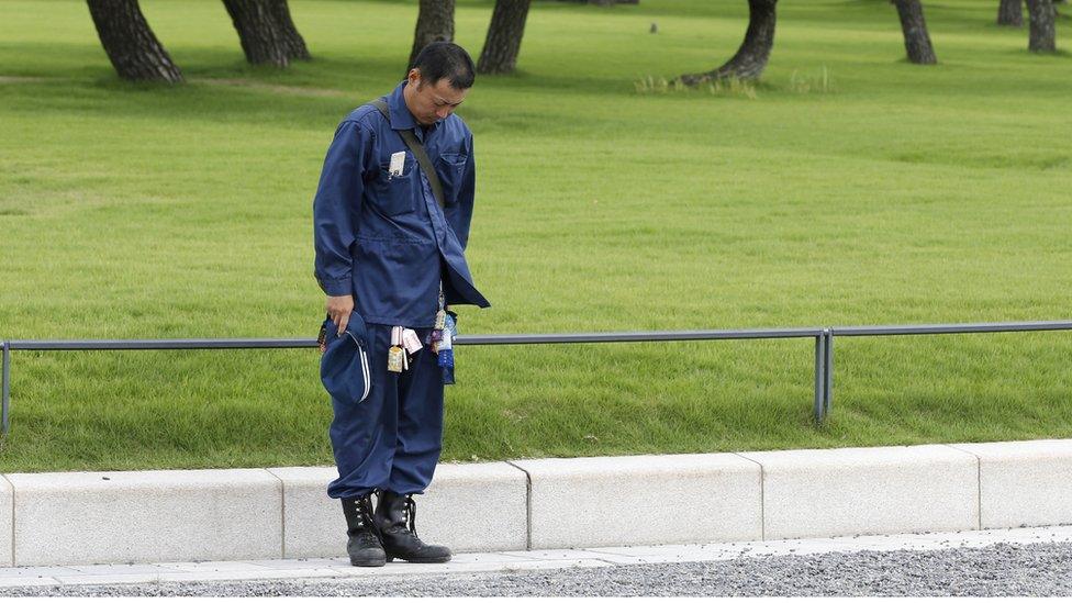 A man bows toward the Imperial Palace while listening to Emperor Akihito's message in Tokyo, Monday, Aug. 8, 2016.