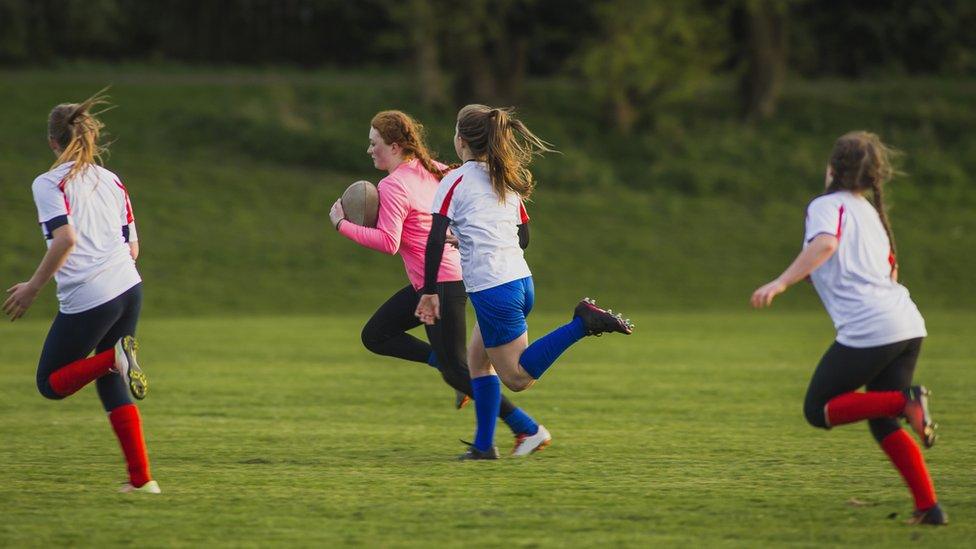 Teenage girls playing rugby