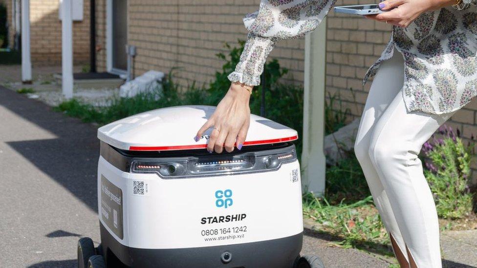 Woman collecting her goods from a delivery robot