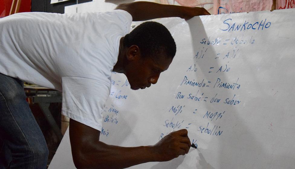 A volunteer writes down words in Palenquero on a whiteboard