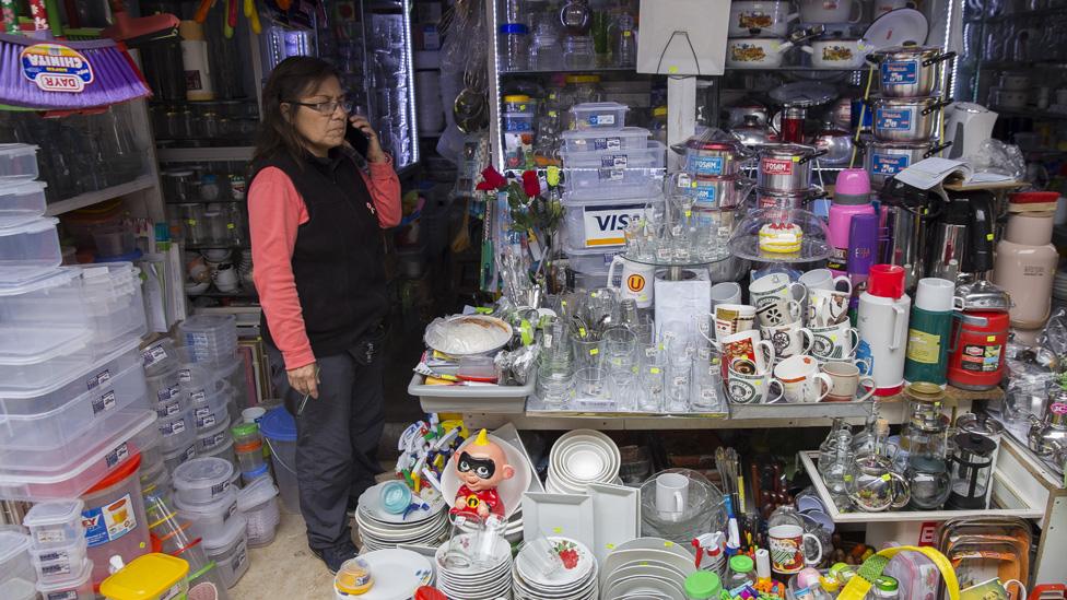 Peruvian merchant Alejandrina Bardales takes a inside her tiny market booth selling home good in Lima, Peru on July 19, 2019.